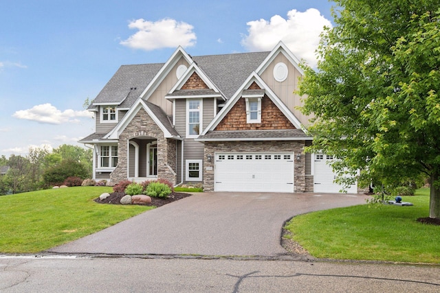 craftsman-style home featuring aphalt driveway, an attached garage, a shingled roof, and a front lawn