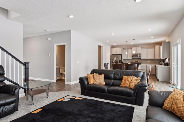 living area featuring stairs, light wood finished floors, recessed lighting, and baseboards