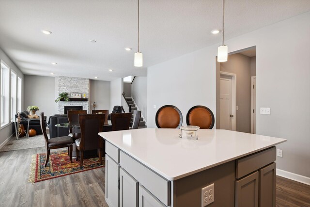 kitchen featuring recessed lighting, a fireplace, light countertops, dark wood finished floors, and decorative light fixtures