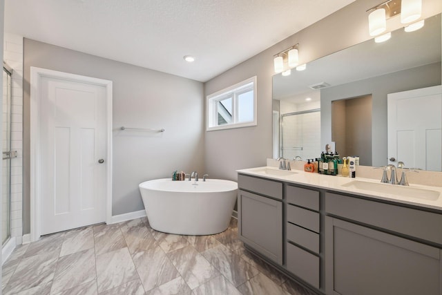 bathroom with a freestanding bath, double vanity, a stall shower, and a sink