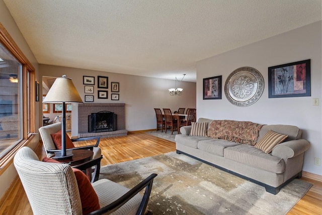 living area with an inviting chandelier, a fireplace, wood finished floors, and a textured ceiling