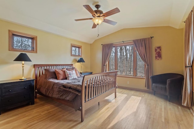 bedroom with light wood-style floors, lofted ceiling, ceiling fan, and baseboards