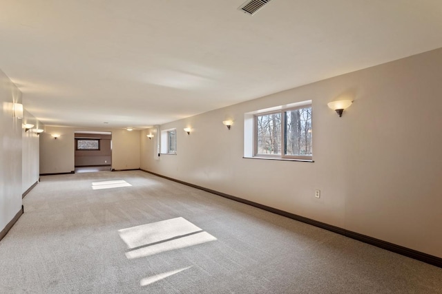 empty room with baseboards, carpet flooring, visible vents, and a healthy amount of sunlight