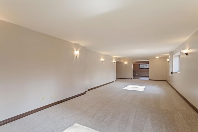 spare room featuring baseboards and light colored carpet