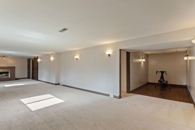 carpeted empty room with visible vents, a fireplace, and baseboards