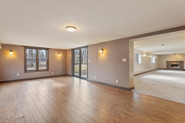 interior space with a wealth of natural light, a fireplace with raised hearth, and wood finished floors