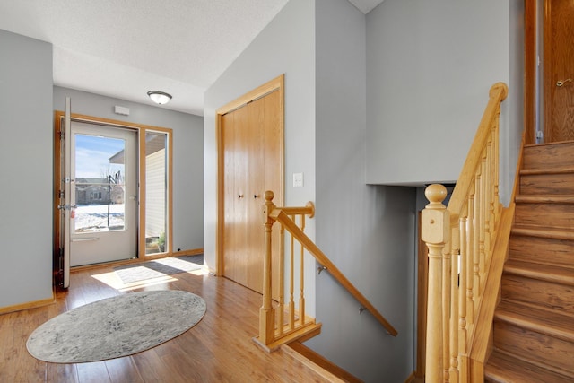 foyer entrance featuring wood finished floors, baseboards, and a textured ceiling