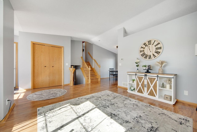 interior space with stairway, lofted ceiling, baseboards, and wood finished floors