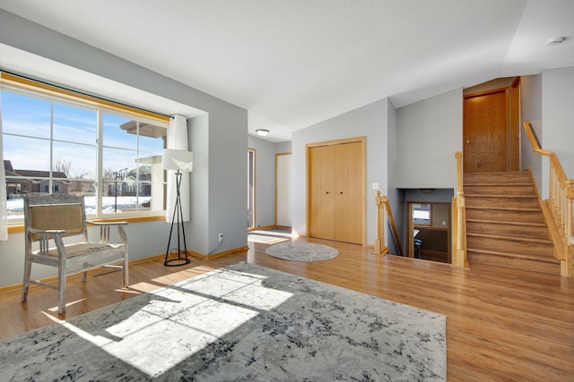 living area with stairway, baseboards, wood finished floors, and vaulted ceiling