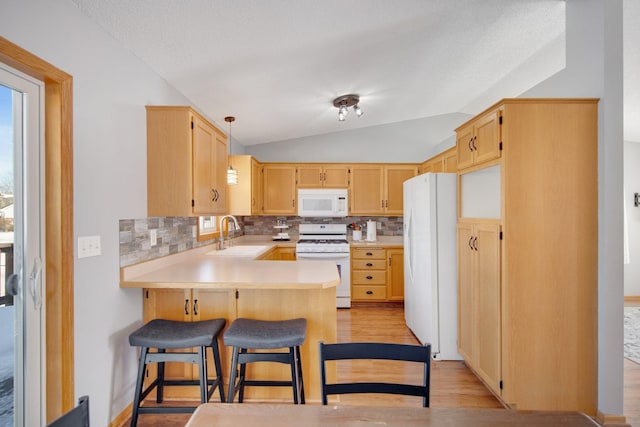 kitchen with lofted ceiling, decorative backsplash, a peninsula, white appliances, and a sink