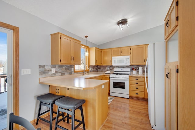 kitchen with a sink, backsplash, white appliances, a peninsula, and lofted ceiling