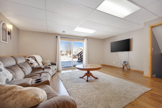 living room featuring light wood-style floors, baseboards, and a drop ceiling