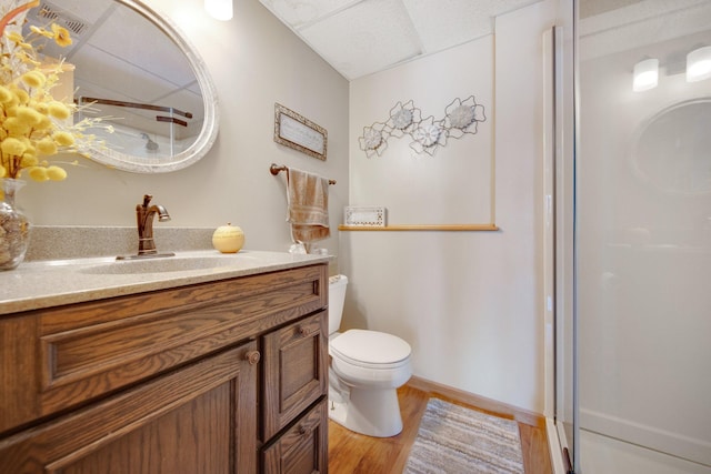 bathroom featuring a shower with door, toilet, vanity, and wood finished floors