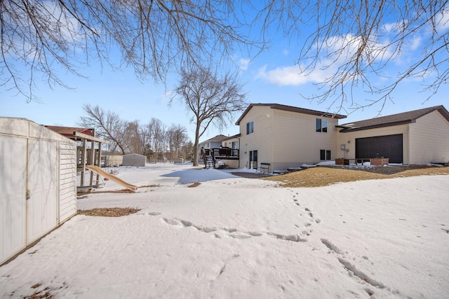 snow covered back of property with a storage shed and an outdoor structure