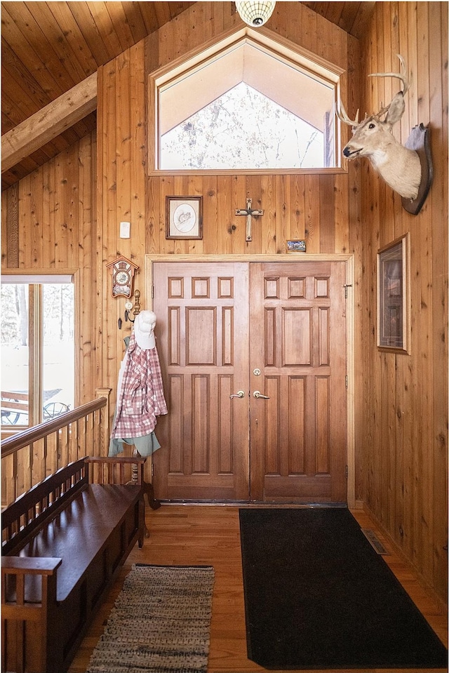 foyer with lofted ceiling, plenty of natural light, wood ceiling, and wooden walls