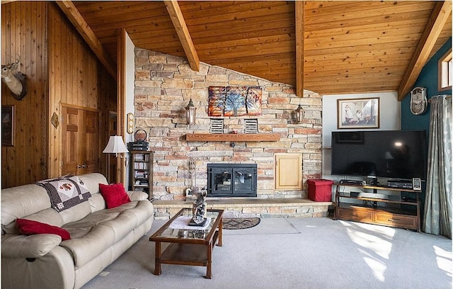 carpeted living room with wooden walls, wood ceiling, vaulted ceiling with beams, and a stone fireplace