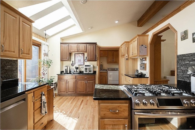 kitchen featuring light wood finished floors, tasteful backsplash, washer / dryer, lofted ceiling with beams, and stainless steel appliances