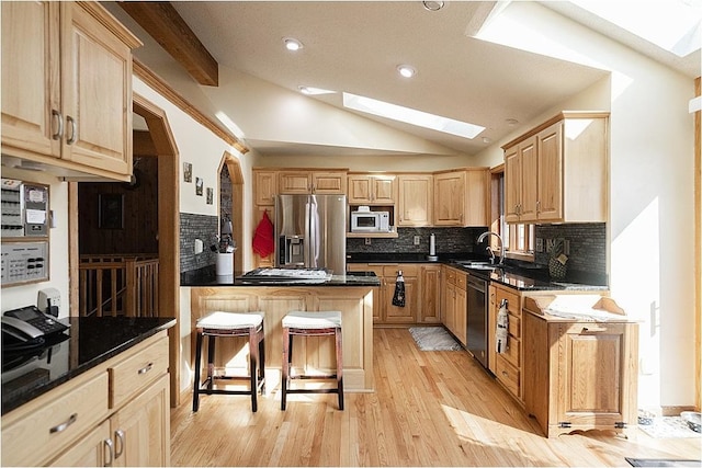 kitchen featuring stainless steel fridge with ice dispenser, dishwashing machine, white microwave, lofted ceiling with skylight, and light brown cabinetry