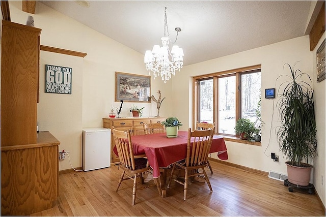 dining space featuring a notable chandelier, visible vents, baseboards, vaulted ceiling, and light wood-type flooring