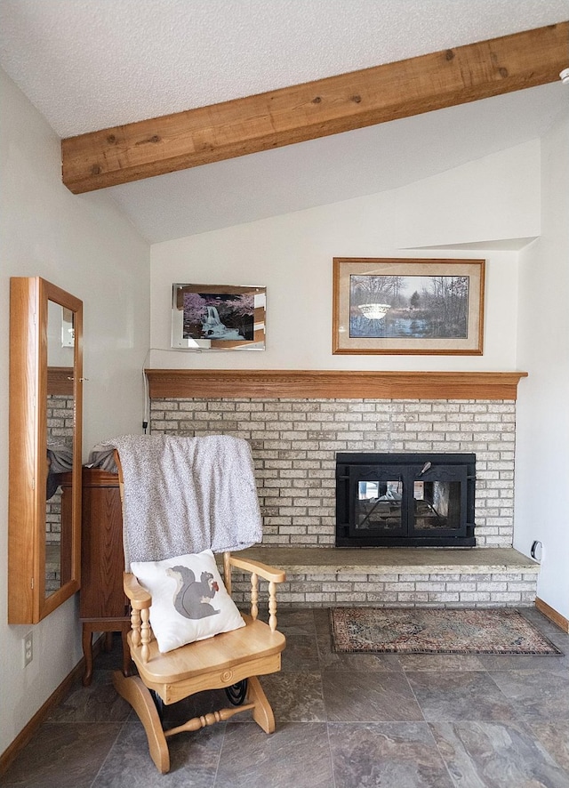 living room with vaulted ceiling with beams, a textured ceiling, a brick fireplace, and baseboards