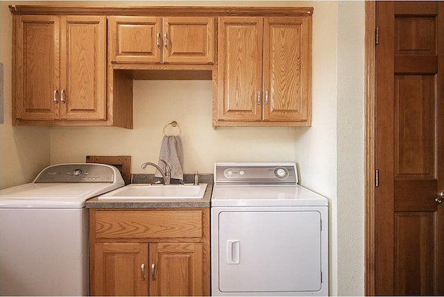 laundry room featuring washing machine and clothes dryer, a sink, and cabinet space