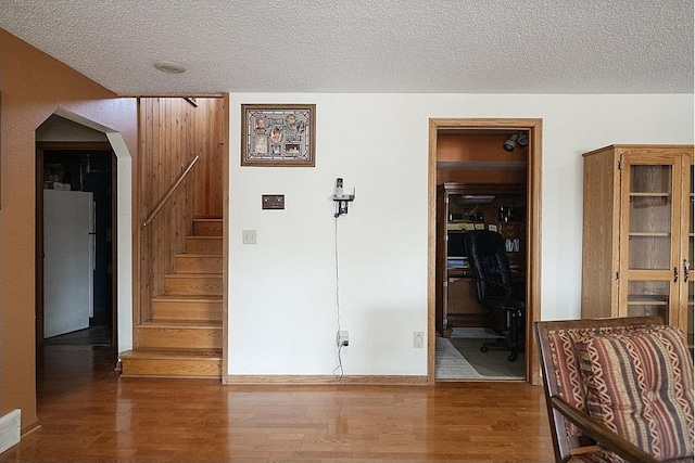 interior space featuring arched walkways, visible vents, stairway, a textured ceiling, and wood finished floors