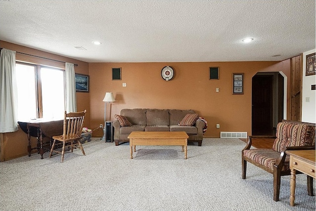 carpeted living room with arched walkways, a textured ceiling, recessed lighting, visible vents, and baseboards