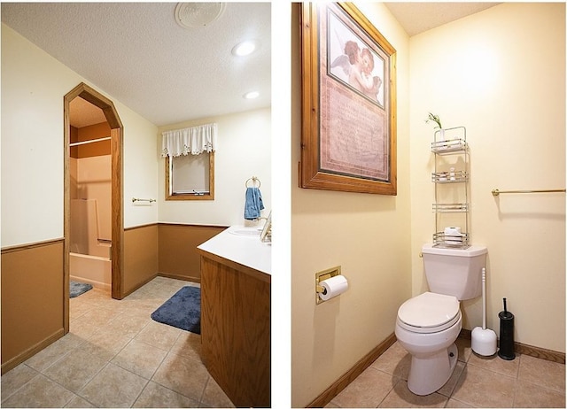 bathroom featuring toilet, a textured ceiling, vanity, baseboards, and tile patterned floors