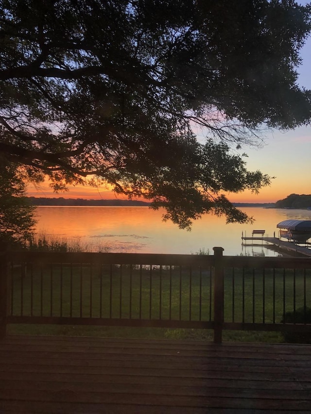 deck at dusk featuring a water view