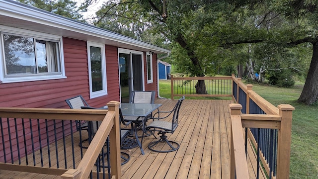 deck with outdoor dining area and a yard