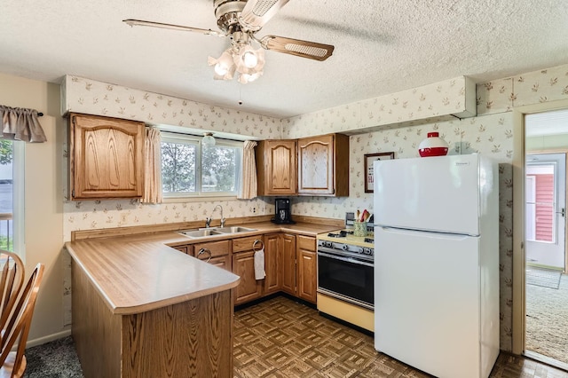 kitchen featuring freestanding refrigerator, gas range, and wallpapered walls