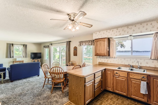 kitchen with open floor plan, a textured ceiling, a sink, and a wealth of natural light