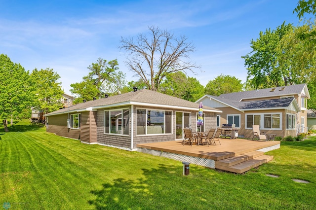 back of property with roof with shingles, a deck, and a yard