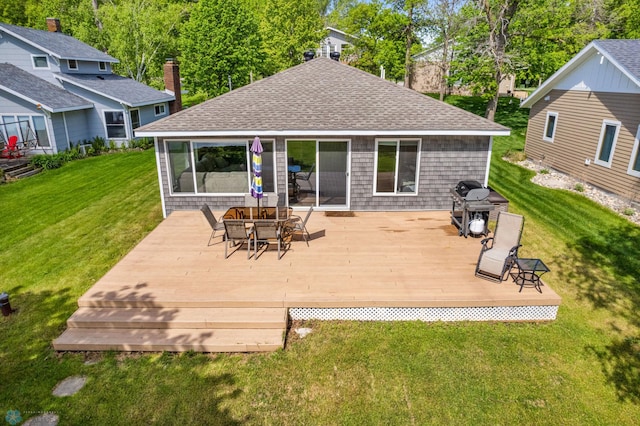 rear view of house featuring a deck, roof with shingles, and a lawn