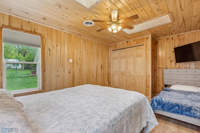 bedroom featuring wooden ceiling, a skylight, visible vents, and wood walls