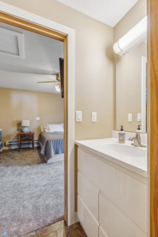 ensuite bathroom with a textured ceiling, ceiling fan, a baseboard radiator, vanity, and ensuite bath