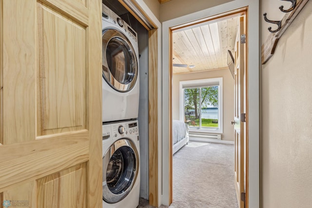 laundry area with stacked washer and dryer, carpet flooring, and baseboards