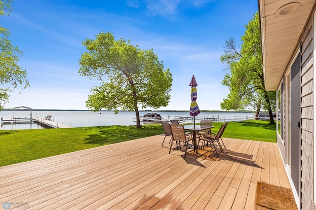 wooden deck featuring outdoor dining space, a water view, a yard, and a boat dock