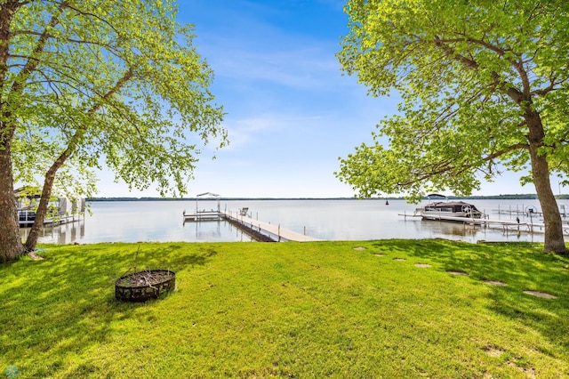 view of dock with a water view, boat lift, and a lawn