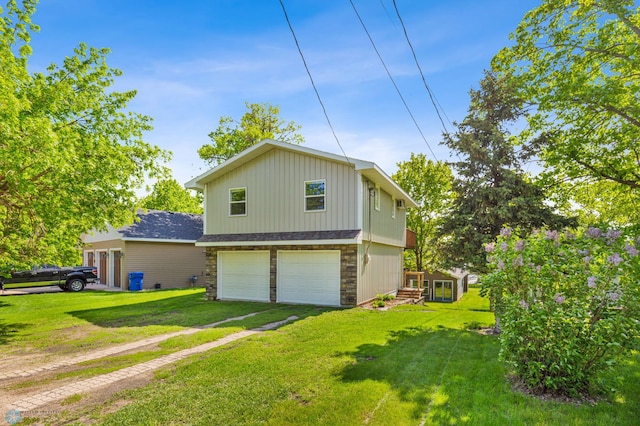 exterior space with a yard, stone siding, driveway, and an attached garage