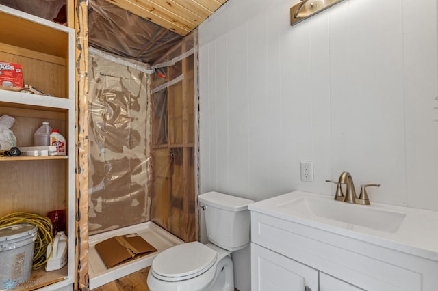 bathroom with a shower stall, toilet, and vanity