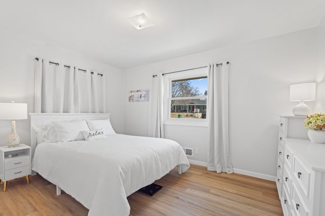 bedroom featuring visible vents, baseboards, and light wood-style floors