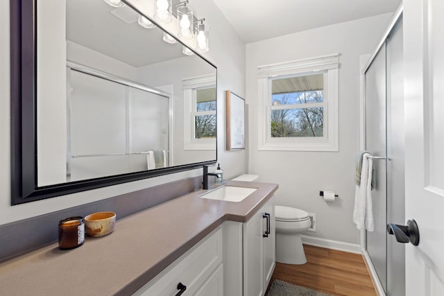 bathroom with vanity, wood finished floors, baseboards, a shower stall, and toilet