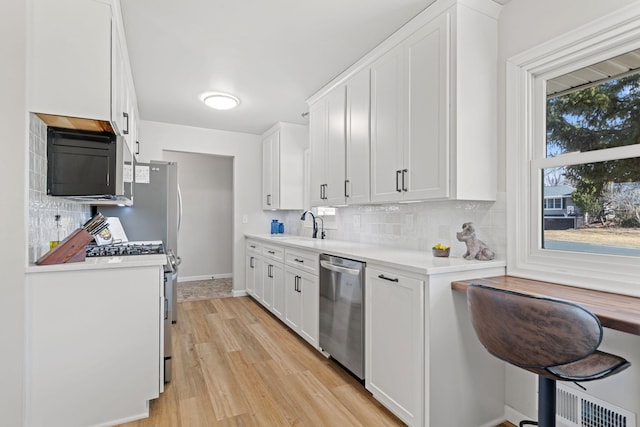 kitchen featuring decorative backsplash, light countertops, white cabinets, and stainless steel appliances