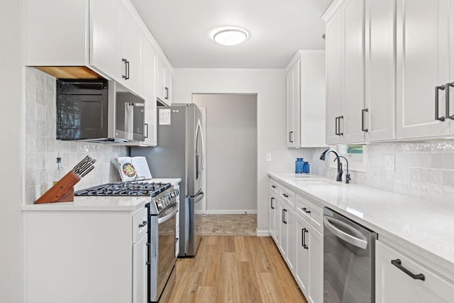 kitchen featuring light wood finished floors, a sink, light countertops, appliances with stainless steel finishes, and white cabinetry