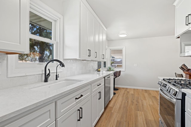 kitchen with tasteful backsplash, plenty of natural light, white cabinets, stainless steel appliances, and a sink