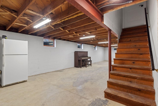 basement with stairs and freestanding refrigerator