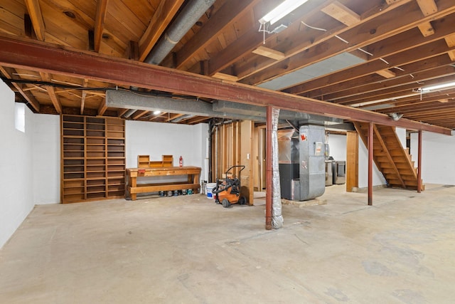 unfinished below grade area featuring stairs, heating unit, and separate washer and dryer