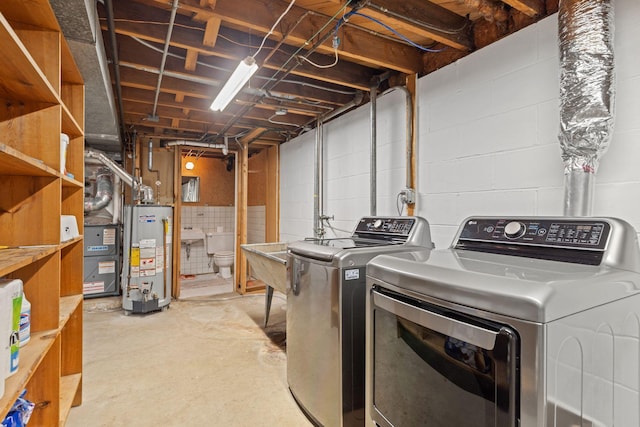 clothes washing area featuring washing machine and dryer, water heater, and laundry area