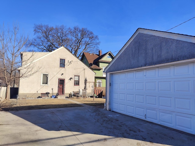 view of front of home featuring a garage, fence, an outbuilding, and stucco siding